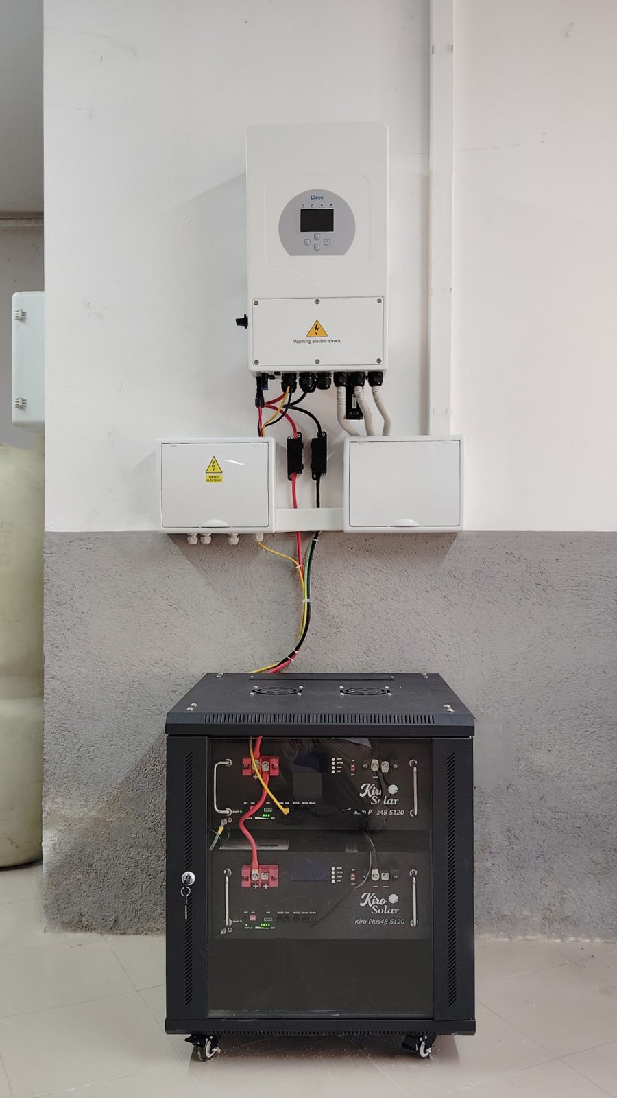 Inversor híbrido Deye sobre un rack de baterías modulares en la pared de una vivienda
